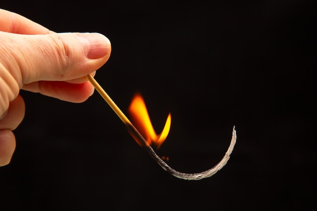 Foto fuego y humo cerilla encendida en la mano sobre un fondo negro calor y luz de la llama del fuego