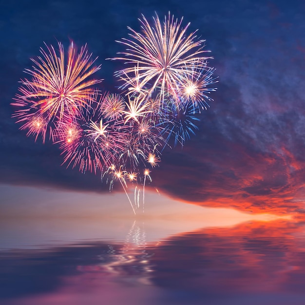 Fuegos artificiales en el cielo en forma de reflejo de corazón en el agua