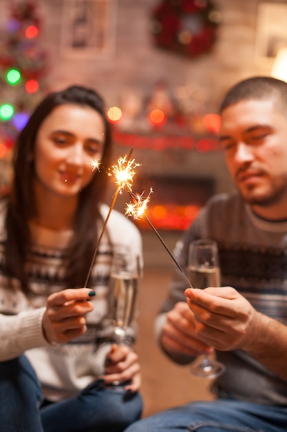 Fuegos artificiales de mano brillante retenidos por pareja joven el día de Navidad.