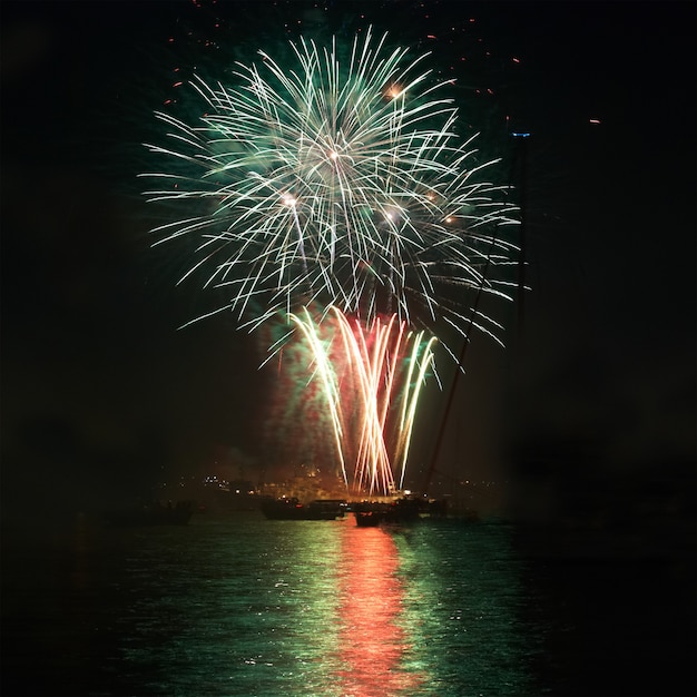 Fuegos artificiales de vacaciones de colores verdes en el cielo negro