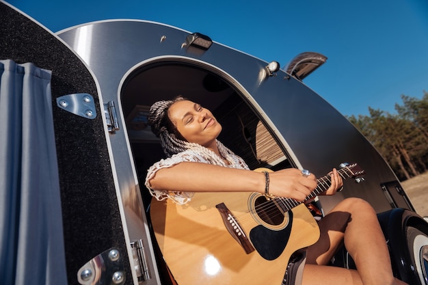 Fühle mich großartig. Afroamerikanischer Musiker mit weißen Dreadlocks, die sich beim Gitarrenspiel großartig fühlen