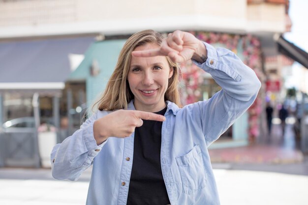 Foto fühlen glücklich freundlich und positiv lächelnd und machen ein porträt oder einen fotorahmen mit den händen