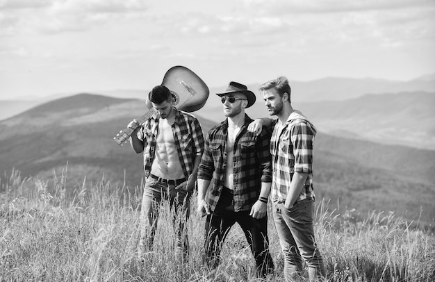 Fühlen Sie sich frei und entspannt glückliche Männer Freunde mit Gitarre Freundschaft Wandern Abenteuer Cowboy Männer Western Camping Lagerfeuer Lieder Männer mit Gitarre im karierten Hemd Menschen verbringen ihre Freizeit zusammen