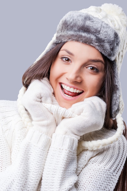 Fühlen Sie sich warm und glücklich. Glückliche junge Frauen, die warme Winterkleidung tragen, während sie vor grauem Hintergrund stehen