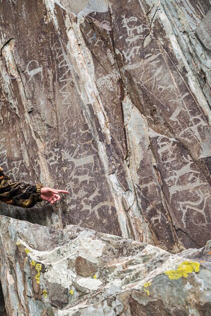 Führen Sie die Hand, die auf Petroglyphen auf einem Felsen zeigt Foto aufgenommen am AdyrKan-Schrein im Altai-Gebirge