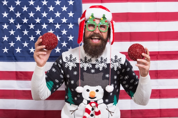 Füllen Sie Ihr Zuhause mit Dekoration. Glücklicher amerikanischer Weihnachtsmann. Bärtiger Mann hält glänzende Weihnachtsdekoration. Kugelverzierung und Dekoration. Feiertagsdekor. Funkelnder Christbaumschmuck. Mit Freude Weihnachten dekorieren.