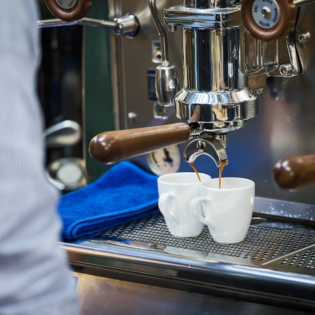 Füllender espresso der kaffeemaschine-maschine in der weißen schale.