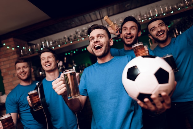 Fünf Fußballfans, die Bier trinken und in der Bar feiern