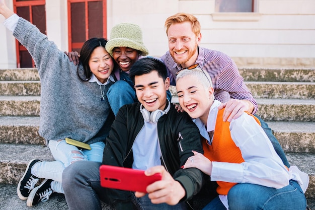 Fünf gemischtrassige Freunde, die ein Foto mit einem Smartphone machen, lächeln und gemeinsam Spaß haben