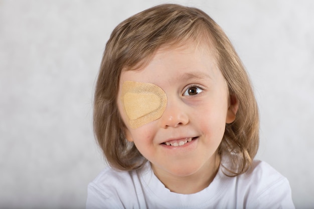 Fünf Jahre alter Junge mit einem Auge, das von einem Augenpad bedeckt ist, und mit einer Brille.