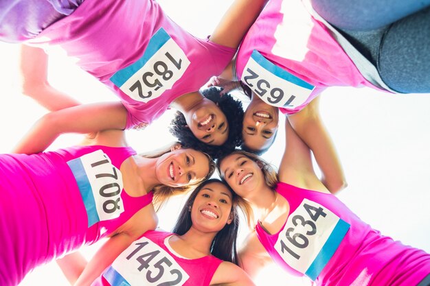 Fünf lächelnde Läufer, die Brustkrebsmarathon stützen