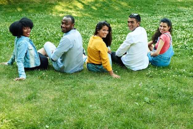 Fünf schwarze Menschen sitzen zusammen auf dem Rasen. Eine Gesellschaft von Freunden