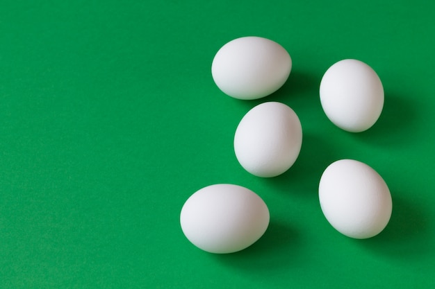 Fünf weiße Eier liegen auf einem üppig grünen Hintergrund dieses Kopierraums. Billardkonzept.