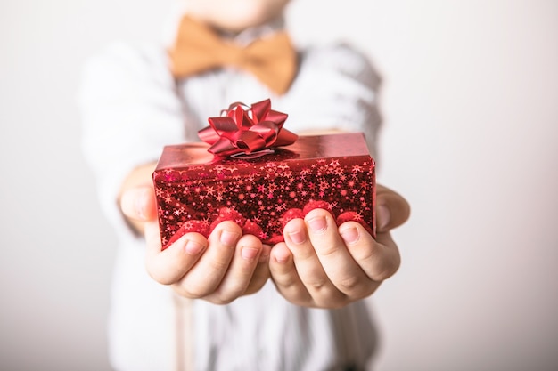 Fünfjähriger lächelnder Junge geben ein rotes Geschenk