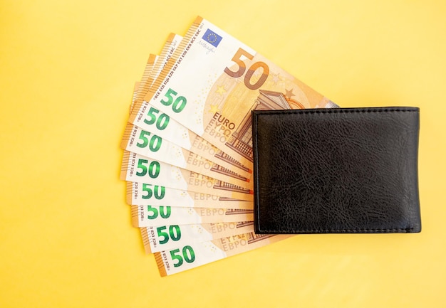 Fünfzig Euro-Banknoten in einer schwarzen Brieftasche auf gelbem Hintergrund, Bargeldpapierwährung, Zahlung,