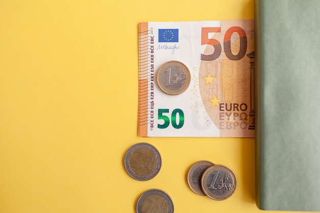 Fünfzig Euro-Banknoten in einer schwarzen Brieftasche auf gelbem Hintergrund