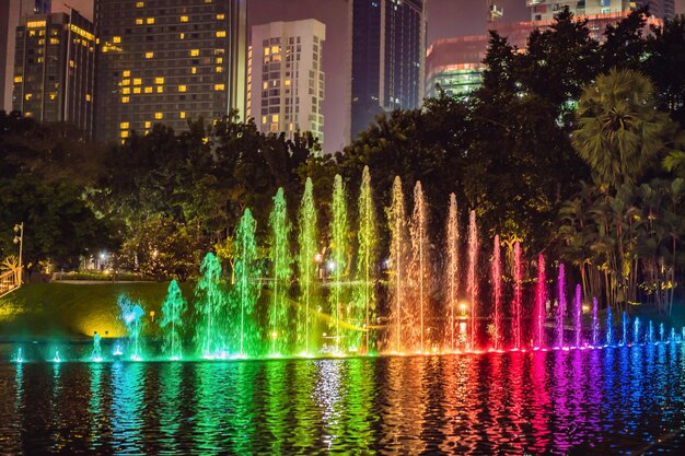 La fuente colorida en el lago por la noche cerca de las Torres Gemelas con la ciudad al fondo Kuala Lumpur Malasia