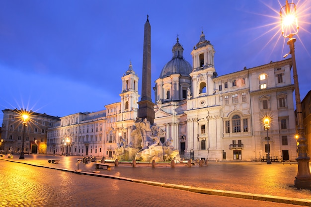 Fuente de los Cuatro Ríos con un obelisco egipcio y la iglesia de Sant Agnese en la famosa plaza Piazza Navona en la noche, Roma, Italia.