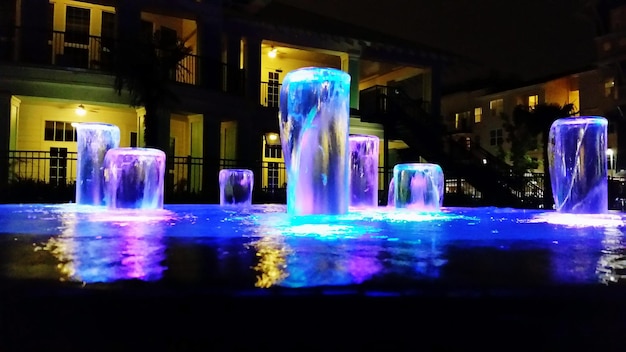 Fuente iluminada contra el edificio por la noche