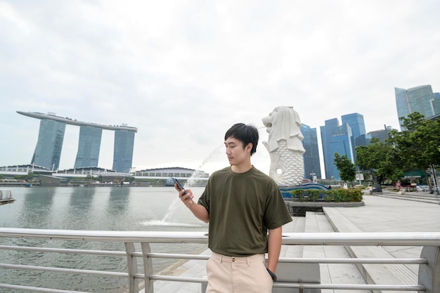 Fuente Merlion frente a la bahía de Marina con un joven turista asiático