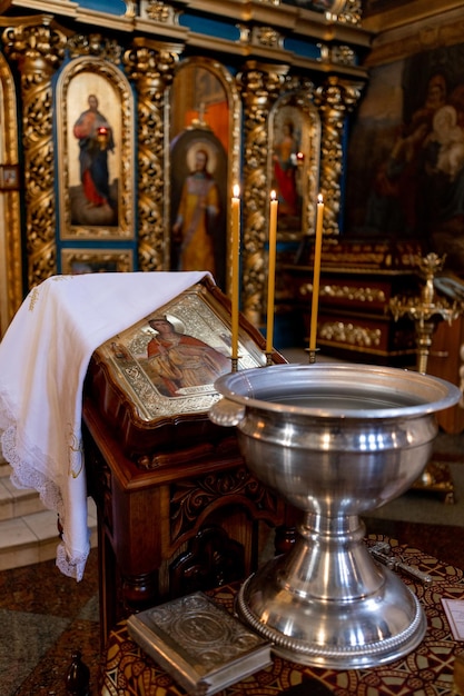 Fuente de metal para bautizo en la iglesia con velas