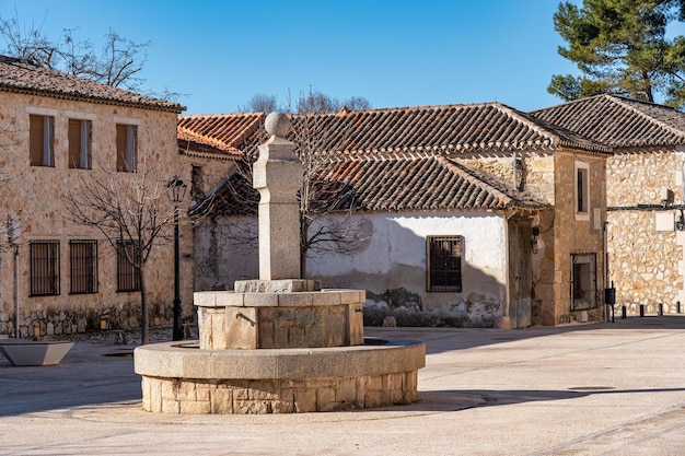 Fuente de piedra en una plaza con edificios antiguos del pueblo medieval de Nuevo Baztan Madrid