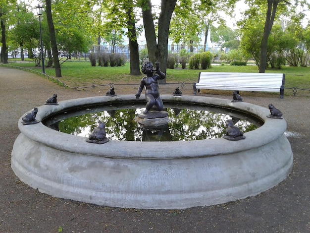 Fuente en la plaza Nikolsky Escultura de un niño con ranas Reflejo de árboles en el agua