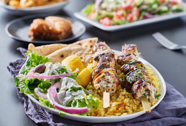 Fuente de souvlaki de pollo griego con pan de pita, ensalada y arroz