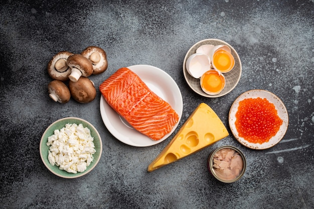 Fuentes naturales de vitamina D: salmón fresco, caviar, queso, champiñones, atún, huevos en la vista superior de fondo de piedra gris. Alimentos y productos ricos en vitamina D. Alimentos saludables que contienen vitamina D