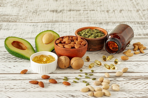 Fuentes vegetales de ácidos omega-3. Concepto de dieta equilibrada. Aguacate, nueces, aceites sobre fondo de madera,