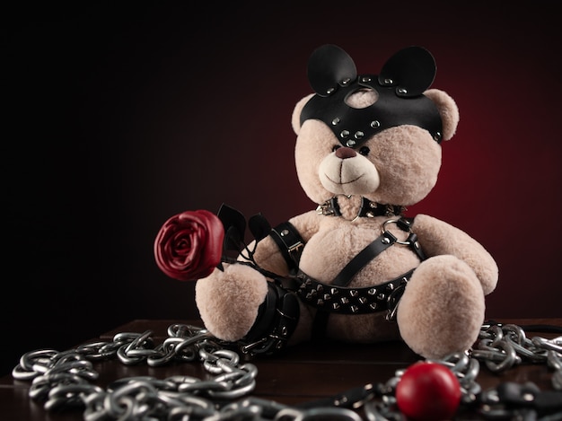 Für BDSM ist ein Spielzeug-Teddybär in Ledergürtel und eine Maske ein Accessoire