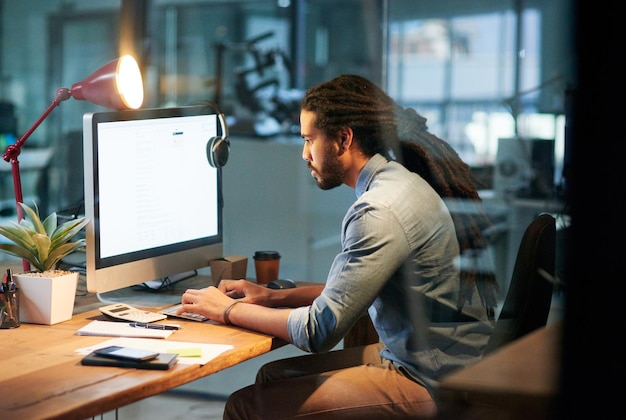 Für den Erfolg arbeiten, während andere davon träumen Schnappschuss eines jungen Designers, der spät am Computer in einem Büro arbeitet