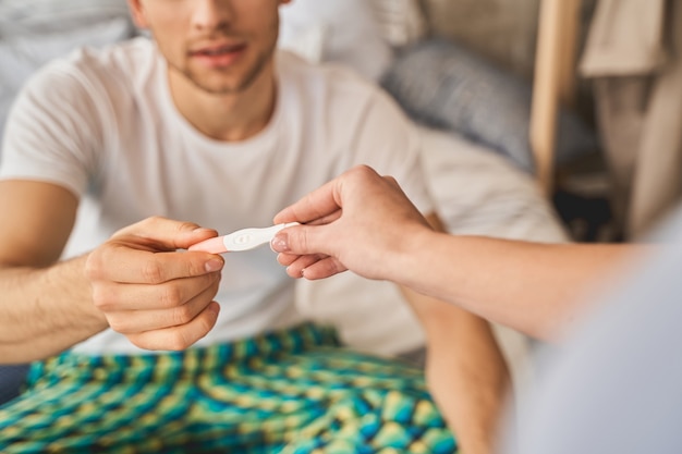 Für dich. Überraschter junger Mann, der auf dem Bett sitzt und seinem Partner zuhört. Gesundheits- und Pflegekonzept