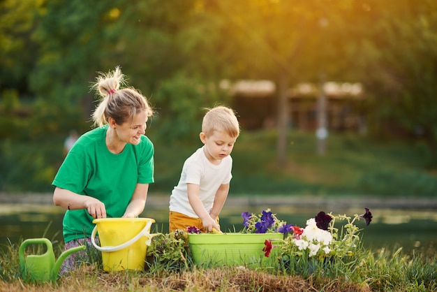 Für die natur sorgen. mutter und sohn pflanzen sämling im boden auf zuteilung am flussufer. botanisches und ökologisches konzept.