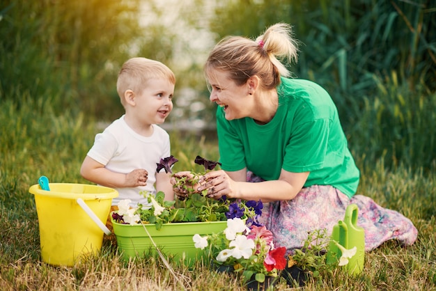 Für die Natur sorgen. Mutter und Sohn pflanzen Sämling im Boden auf Zuteilung am Flussufer. Botanisches und ökologisches Konzept.