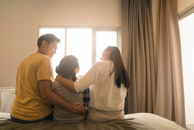 Für immer zusammen lieben asiatische Familienhand zusammen mit morgendlichem Sonnenlicht aus dem Fenster auf dem Bett, Mama, Papa und Daighter halten mit Sorgfalt und Liebe im Schlafzimmer zusammen
