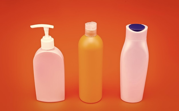 Für Kosmetikverpackungen Verpackungsflaschen Wiederauffüllflaschen mit Flip-Kappen und Pumpendispenser HDPE orangefarbener Hintergrund Kunststoffflüssigkeitsbehälter Schönheitsprodukte Kopierplatz