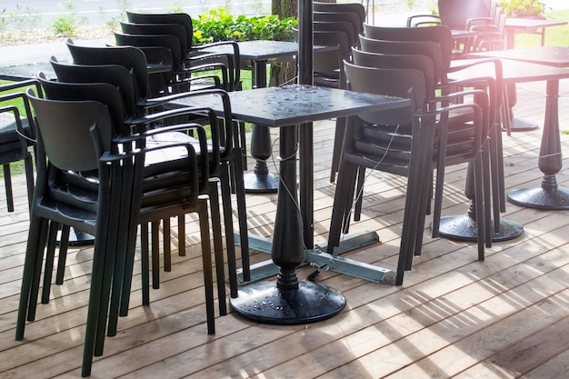 Fuera de la cafetería de verano de pie, sillas apiladas y una mesa cubierta con gotas de lluvia