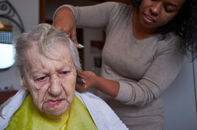 Fürsorgliche afroamerikanische Frau, die ihre Haare zu Hause schneidet.