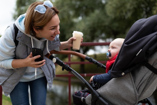 Fürsorgliche junge Mutter schaut dem Kind in den Kinderwagen