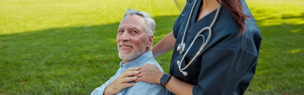 Fürsorgliche Krankenschwester mit Gesichtsschutz und Maske auf einem Spaziergang mit einem alten Mann, der sich in einem Patienten erholt