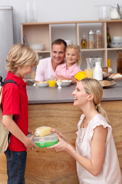 Fürsorgliche Mutter, die das Schulessen zu seinem Sohn packt