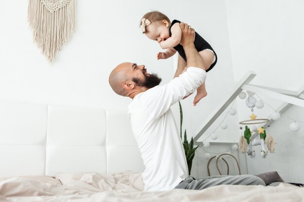 Fürsorglicher Vater spielt mit seiner kleinen Tochter auf dem Bett im Schlafzimmer Liebe und Fürsorge, glückliche Familie, die Zeit miteinander verbringt