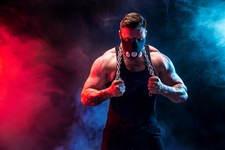 Foto fuerte atleta masculino en una máscara de entrenamiento negro sobre una pared negra