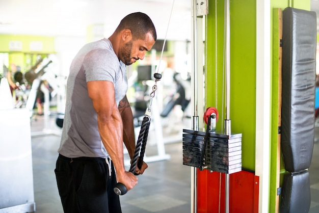 Fuerte guapo deportista haciendo ejercicios de tríceps en el gimnasio