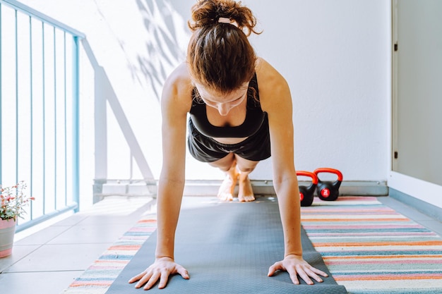 Fuerte joven entrenadora de fitness haciendo tablones para fortalecer bíceps tríceps abs deporte femenino