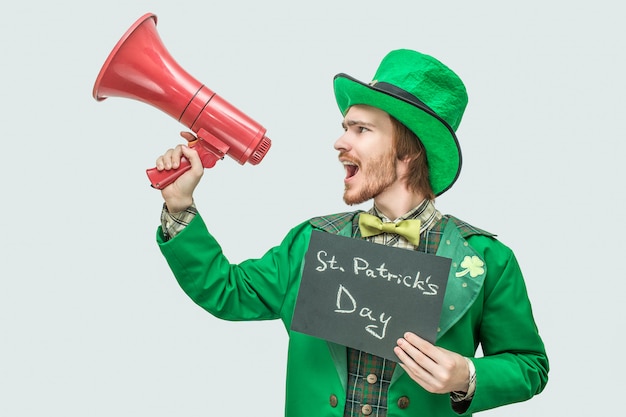 Fuerte joven en traje verde con placa oscura con palabras escritas el día de san patricio.