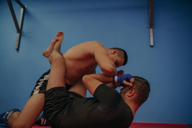 Fuerte luchador de MMA sujetando a su rival y lanzándole golpes durante un entrenamiento. Con un montón de espacio de copia