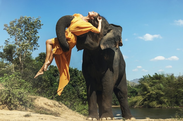 Foto fuerte y poderoso elefante levantando a la joven y hermosa mujer