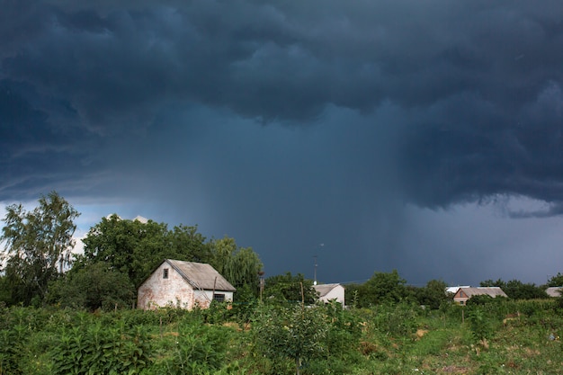 Fuertes lluvias cerca de una vieja casa abandonada en un pueblo distante. Naturaleza verde